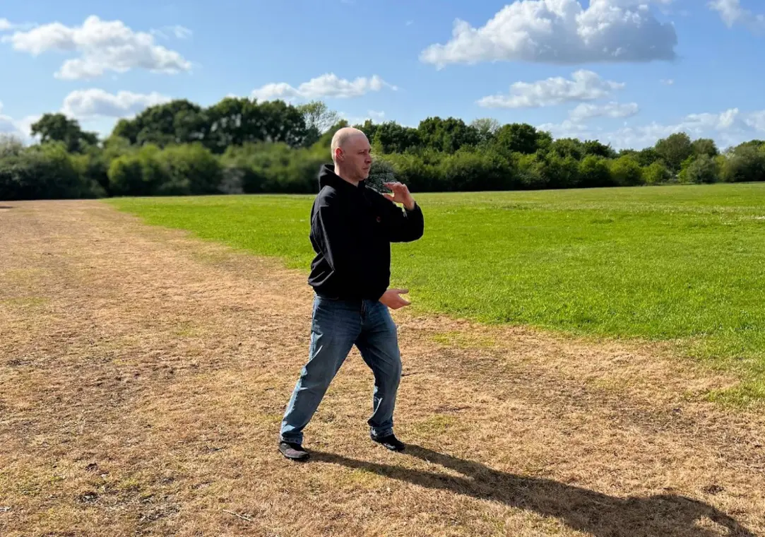Chris practising a Tai Chi posture in an open field