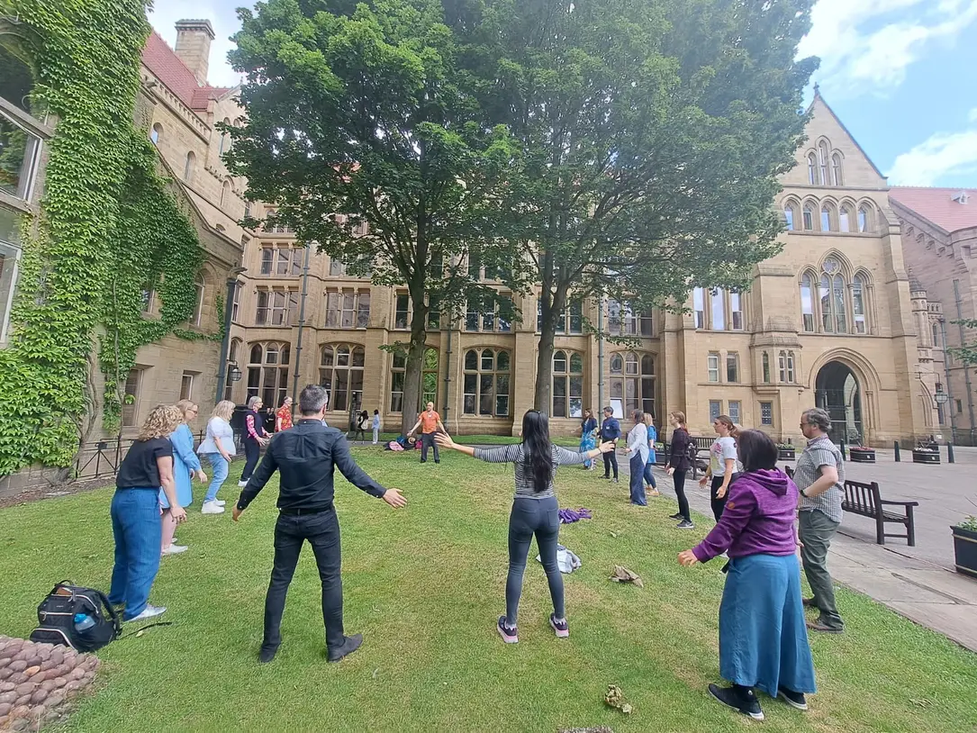 A group practising Qigong outdoors in a university quad in Manchester